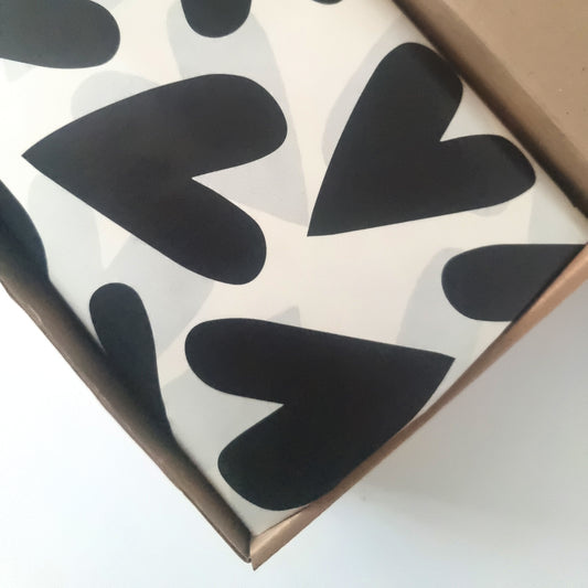 Large hearts printed in black ink on a light stone background in a kraft shipper box